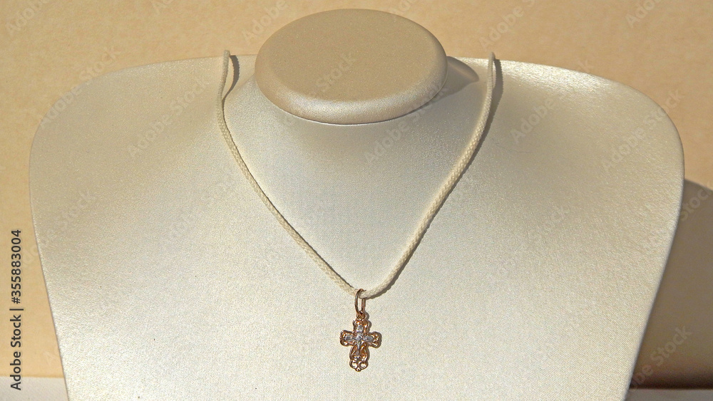golden orthodox cross on a white lace on a jewelry mannequin golden orthodox cross on a white lace on a jewelry mannequin