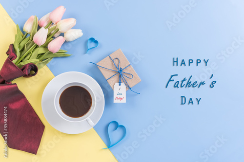 Happy Fathers Day background concept.Decorated red necktie, tulip, blue heart, gift box with tag and coffee cup on bright pastel background with copy space. Top view, flat lay.