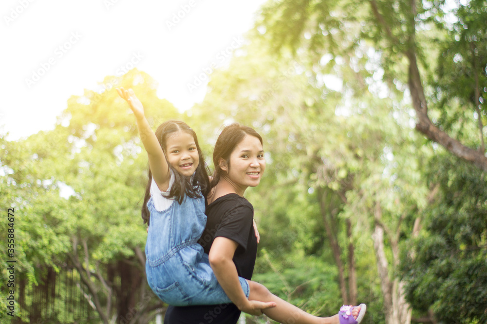Fototapeta premium child piggyback ride playing on mom in nature background