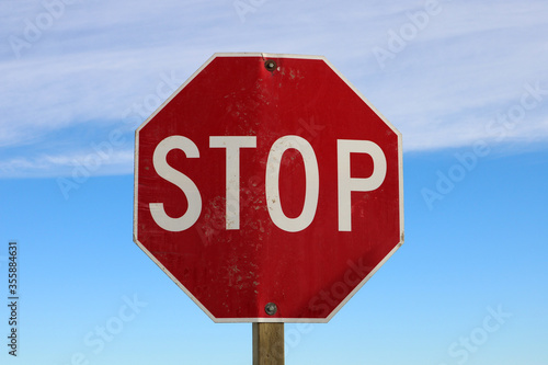 Bright red stop sign. Red sign against a blue sky with a band of high altitude clouds. An visual instruction for drivers.