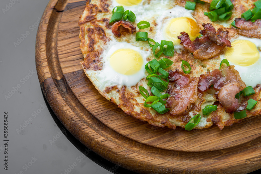 Plate with fried eggs, bacon, tomato and potato griddle cakes close up Plate with fried eggs, bacon, tomato and potato griddle cakes close up