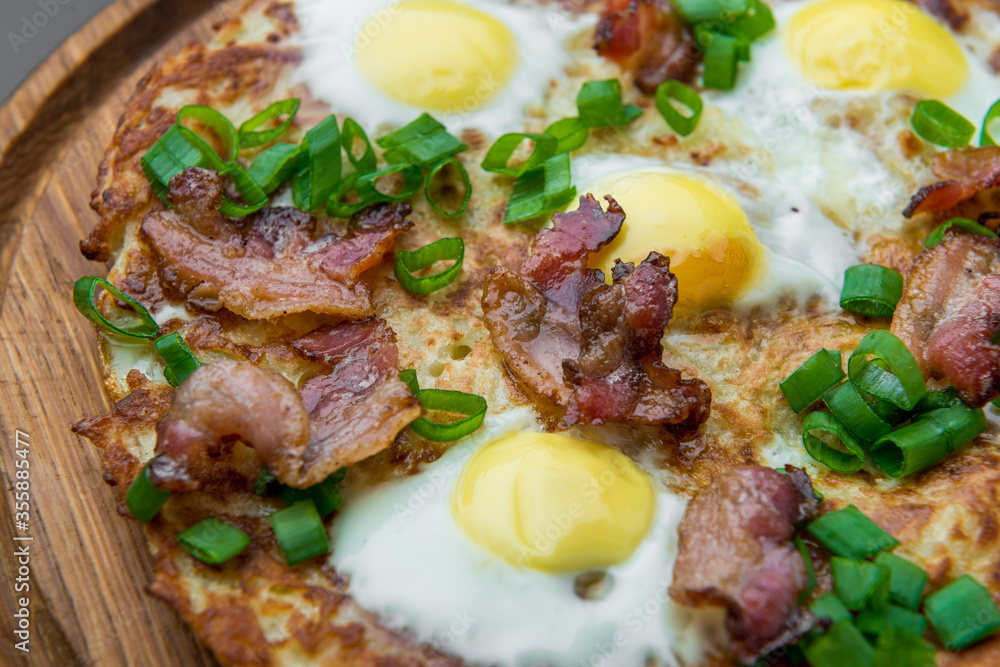 Plate with fried eggs, bacon, tomato and potato griddle cakes close up Plate with fried eggs, bacon, tomato and potato griddle cakes close up