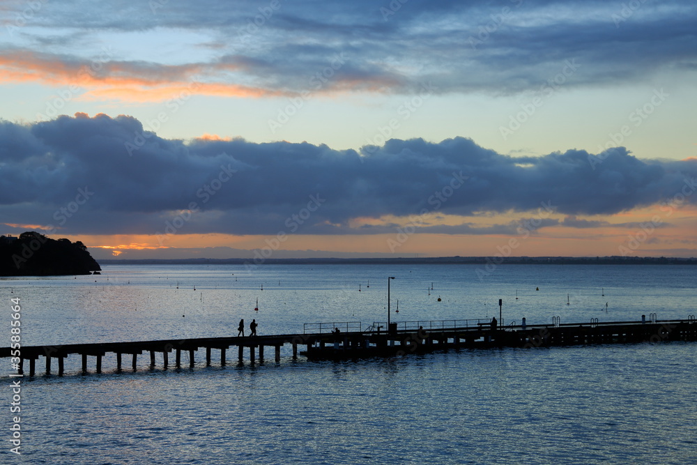 People walking in the breakwater at sunset. Australia People walking in the breakwater at sunset. Australia
