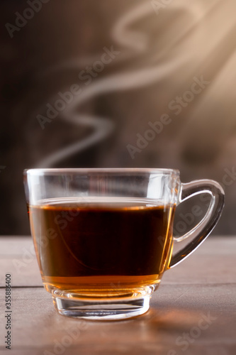Close up hot tea cup on wood table . hot tea in handle glass with copy space for text or design.
