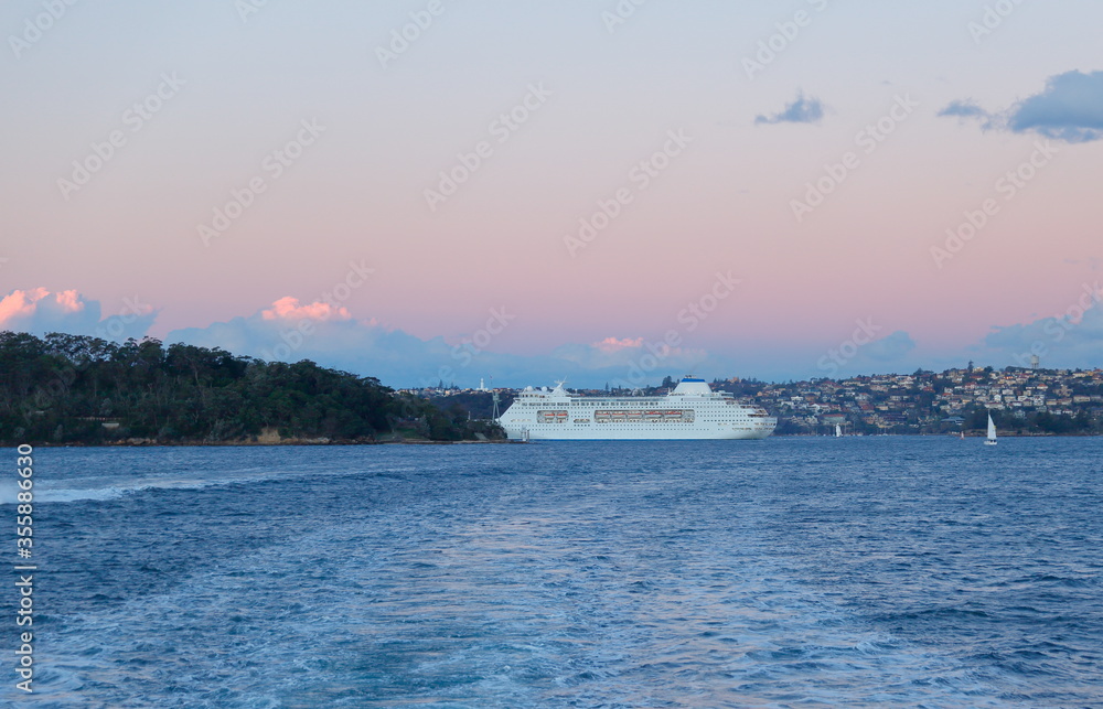 A cruise ship approaching Sydney Harbor at sunset.
