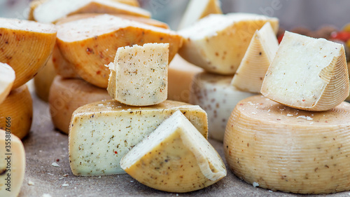 heads of hard cheese are on offer in a choice of cut pieces close-up on theme of dairy farm food.