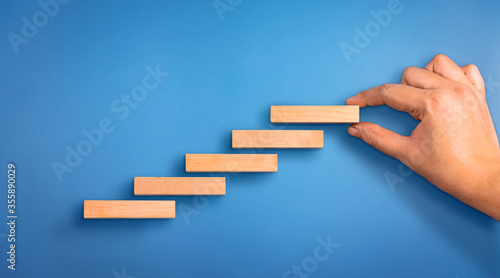 Business person arranging the wooden block steps. Concept of business growth and success. Success steps concept
