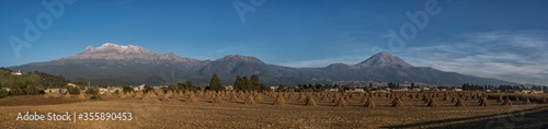 Vista panorámica de los volcanes Popocatepetl e iztaccihuatl con sembradíos recién cultivados en la parte  inferior. photo