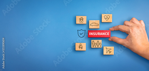 hand holding a wooden block with text insurance, icons and shield icon. Insurance concept, different type of insurance background.