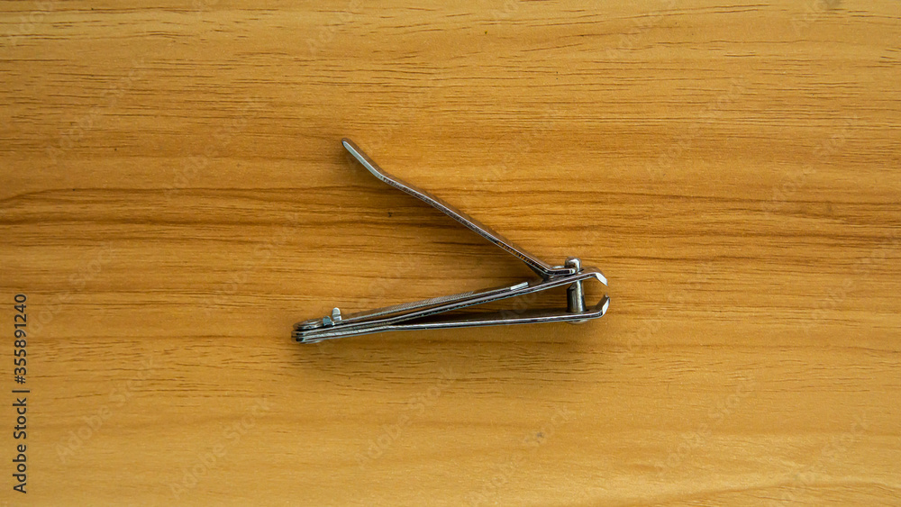Top view grey metal nail clipper on isolated wooden background. Hygiene equipment. Top view grey metal nail clipper on isolated wooden background. Hygiene equipment.
