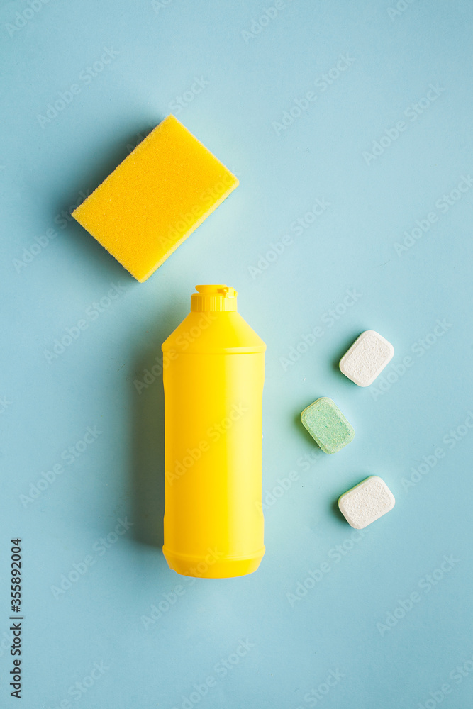 Liquid dishwashing liquid, dishwasher tablets on a blue background. Means for washing dishes. Copy space. Flatlay.