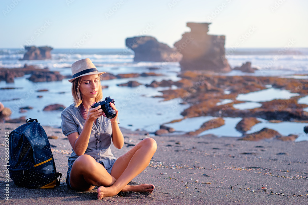 Traveler and photographer. Pretty young woman holding camera on beautiful ocean beach.