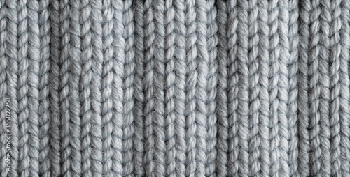 Gray knitted woolen background. Detailed wavy relief knit elastic texture. Handmade dense knitting of thick yarn.Closeup 