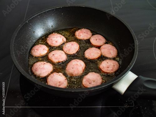 Frying sausage slices in pan