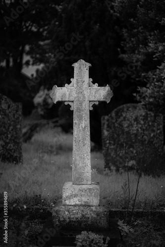 black and white gravestone cross in cemetery graveyard in evening