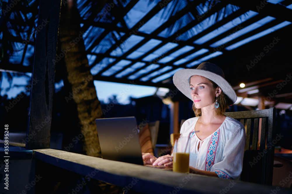 Work and travel. Study and vacation. Working outdoors. Freelance concept. Pretty young woman using laptop in tropical beach bar cafe.