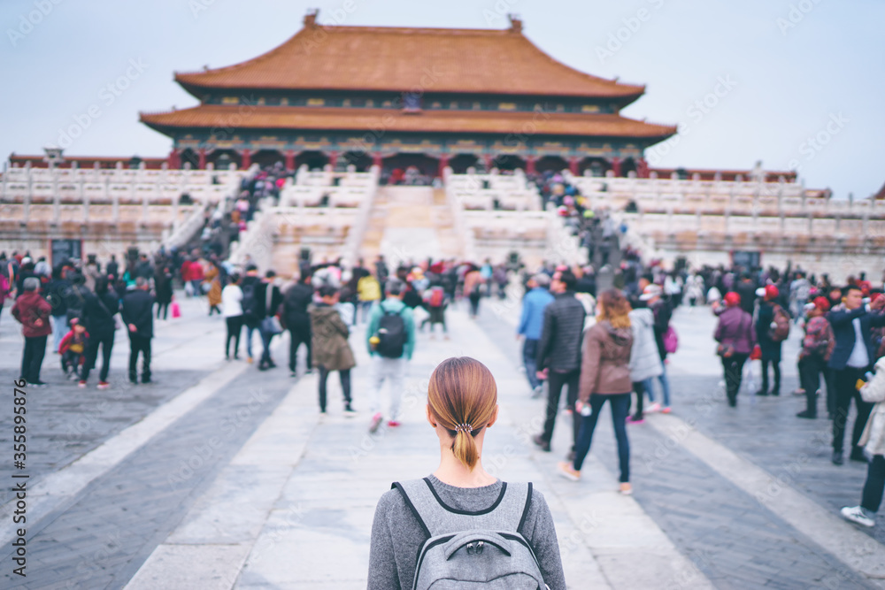 Enjoying vacation in China. Traveling young woman with rucksack in Forbidden City, Beijing.