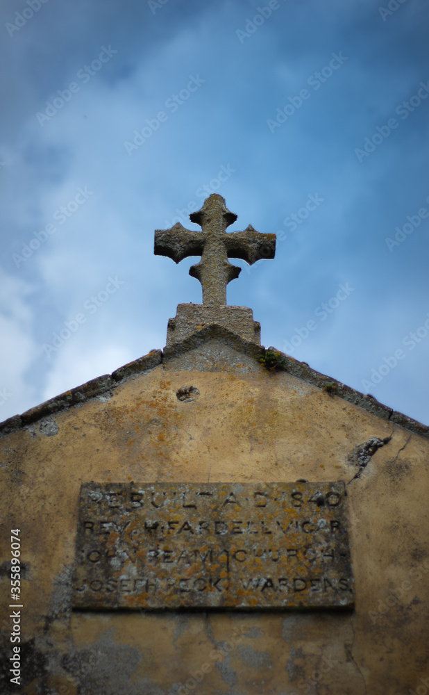 Old cross on ancient church roof with sky england