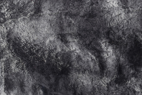 Used lambskin material. Texture of natural sheepskin. Worn uneven gray fur background. Top view. Closeup