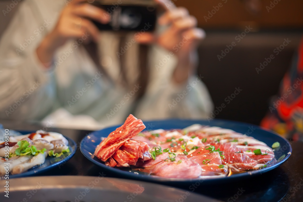 A woman taking food photos with a mobile phone in a restaurant
