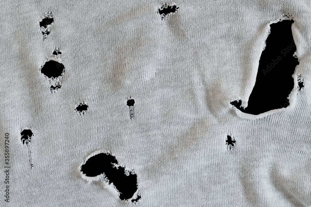 Gray white fabric with many holes. Texture of an old dirty ragged t ...