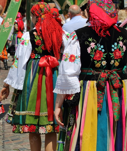Woman in beautiful traditional colroful folk costumes from Lowicz region in Poland while walk in annual Corpus Christi procession