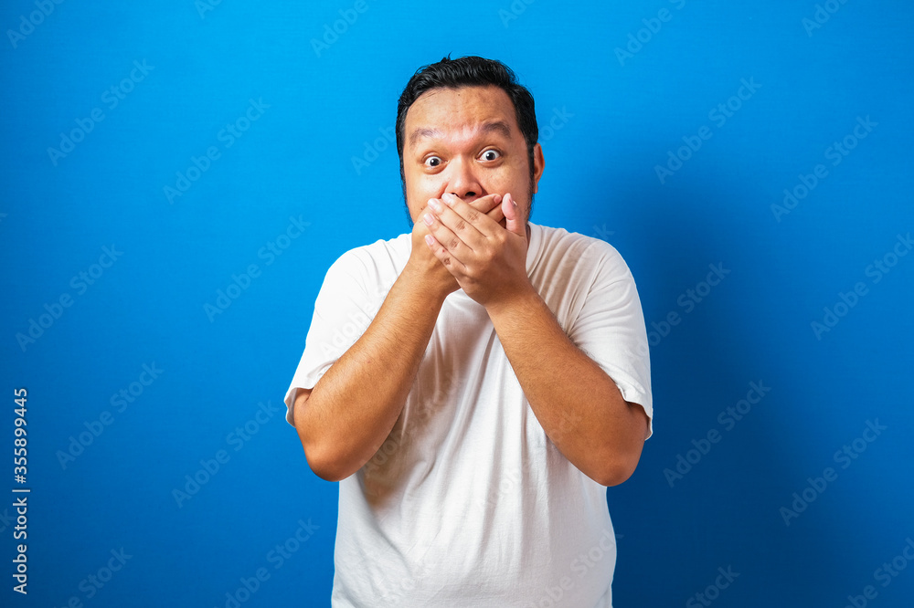 Fat Asian man in white t-shirt shows funny shocked and surprise expression against blue background Fat Asian man in white t-shirt shows funny shocked and surprise expression against blue background