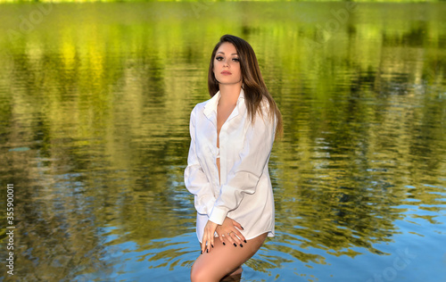 Beautiful girl in white shirt relaxing in river. Summer lifestyle. Gorgeous young woman with stylish makeup