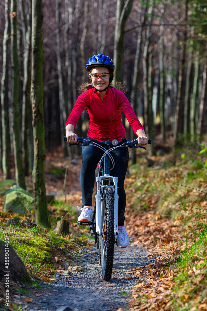 Healthy lifestyle - teenage girl biking in forest
