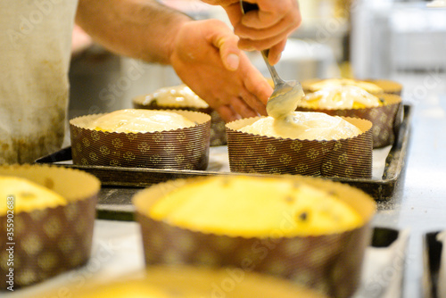 Fototapeta pastry chef in professional kitchen preparing and baking milanese panettone in christmas time