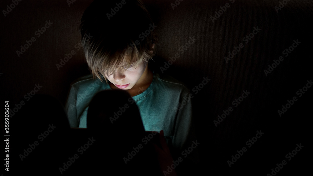 Young boy using smartphones sittingon a sofa at home, entertaining online obsessed with modern devices, gadget addiction Young boy using smartphones sittingon a sofa at home, entertaining online obsessed with modern devices, gadget addiction