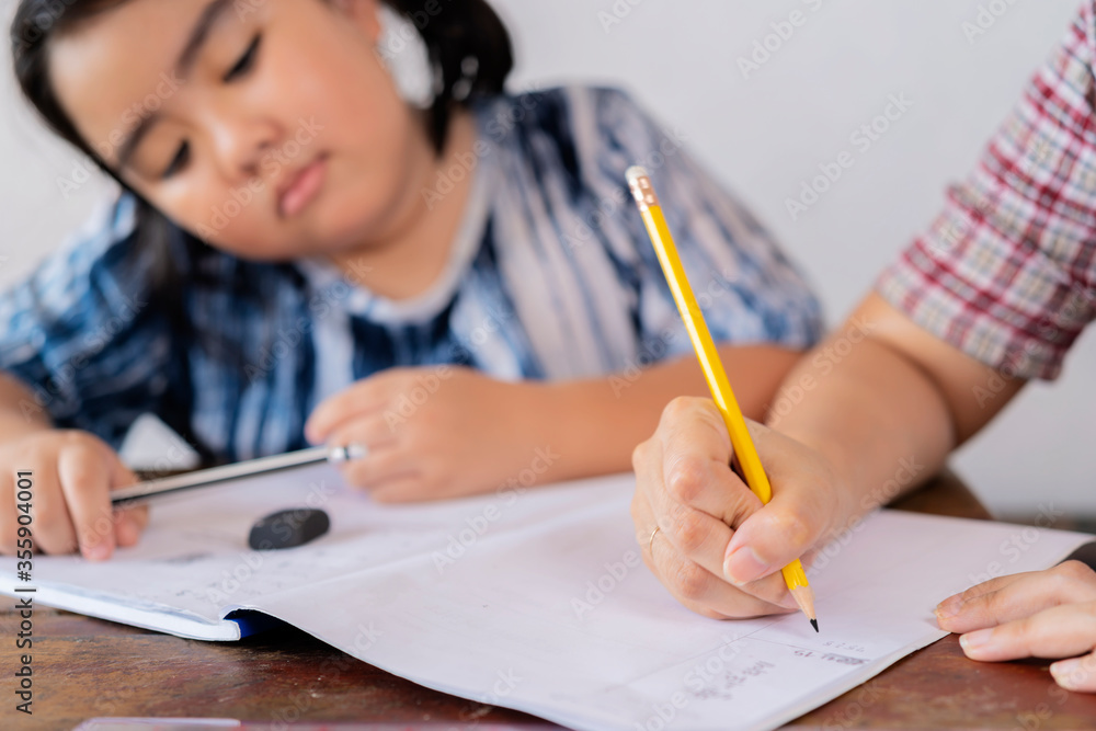 The teacher is teaching an Asian girl. They are learning math