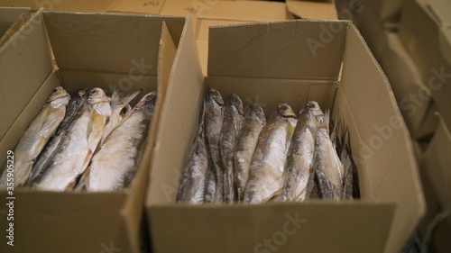 Big fish packs fish in a cardboard box. Large cardboard boxes in stock before shipping. Cardboard boxes with frozen fish. Fish production.