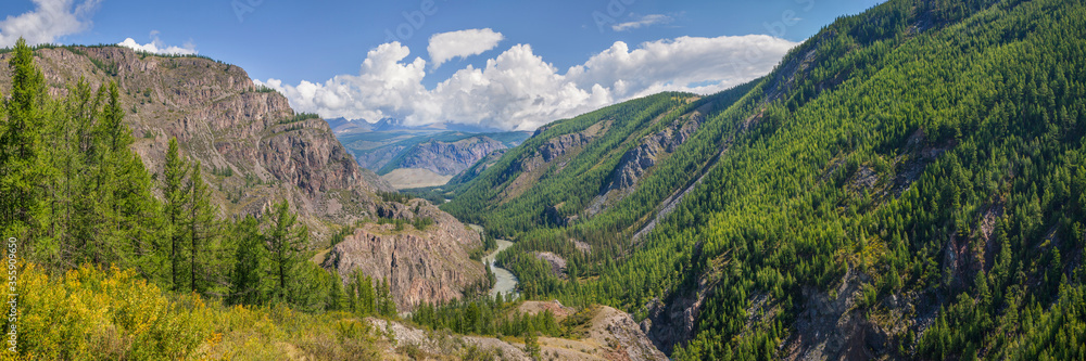 Panoramic view of a mountain valley. Forest, river and blue sky. Summer vacation and travel. Panoramic view of a mountain valley. Forest, river and blue sky. Summer vacation and travel.