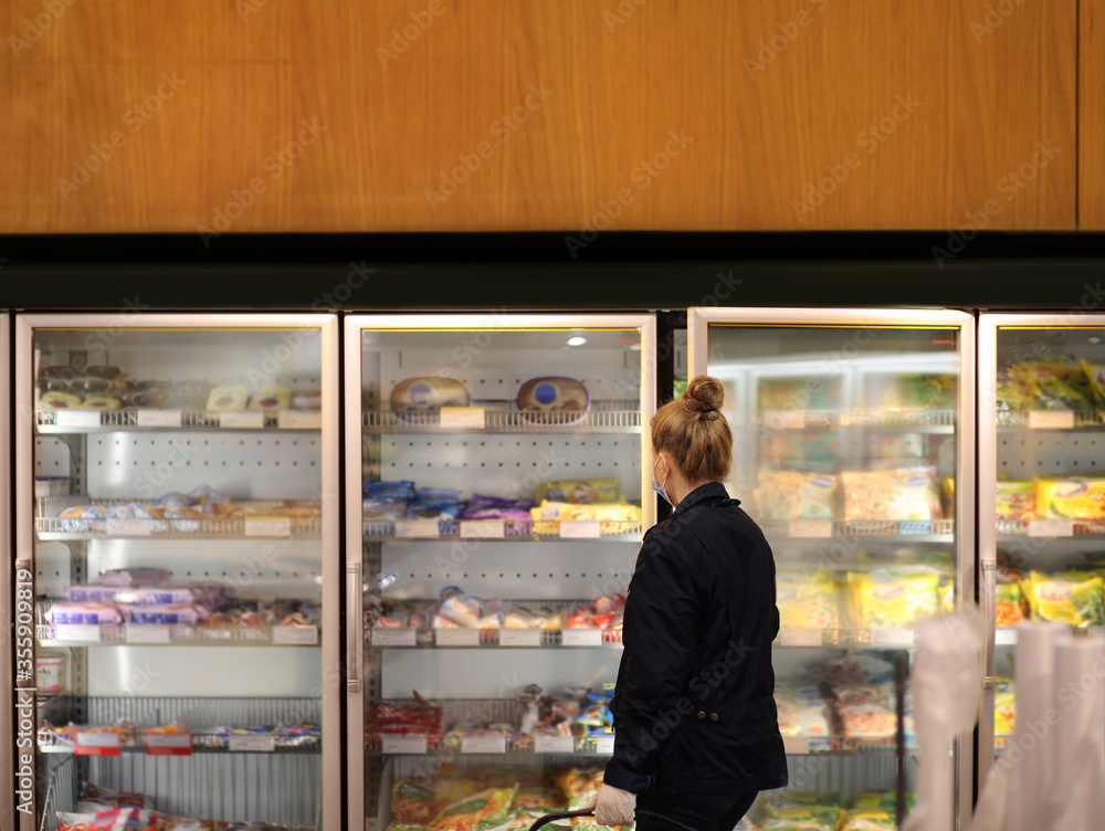 supermarket shopping, face mask and gloves,Woman choosing frozen food from a supermarket freezer