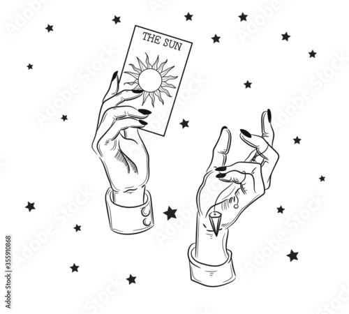 Hands holding a tarot card. The witch bodes from tarot cards, sun, spells and magic