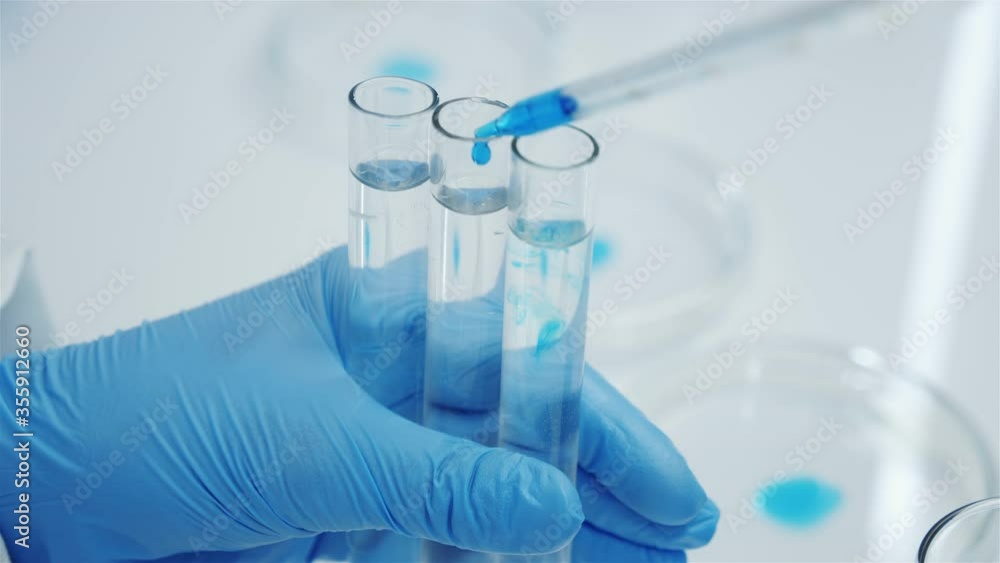 Three laboratory glass test tubes in the hands of a scientist. Conducting experiments. Drop of blue reagent. Perfume production. Three laboratory glass test tubes in the hands of a scientist. Conducting experiments. Drop of blue reagent. Perfume production.