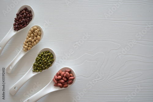 Organic beans: red beans, mung beans, peanuts, soybeans in four white ceramic scoops