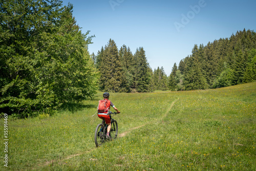 pretty senior woman riding her electric mountain bike on the mountains above Oberstaufen, Allgau Alps, Bavaria Germany 