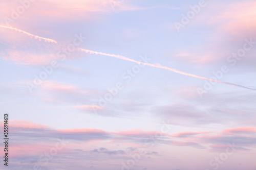 Warm purple sky and clouds at sunset with vapour trails (chemtrails) photo