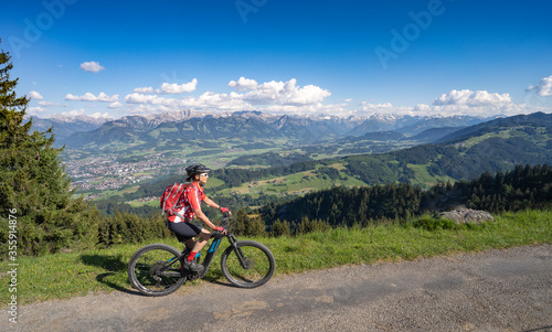 pretty senior woman riding her electric mountain bike on the mountains above the Iller valley between Sonthofen and Oberstdorf, Allgau Alps, Bavaria Germany 