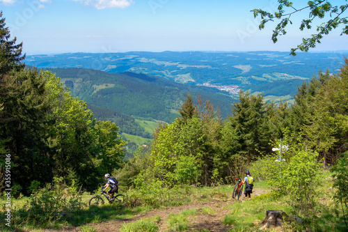 Scenic view of the Black Forest, a large forested mountain range in the southwest of Germany. Two mountain bikers are drive down the hillside.