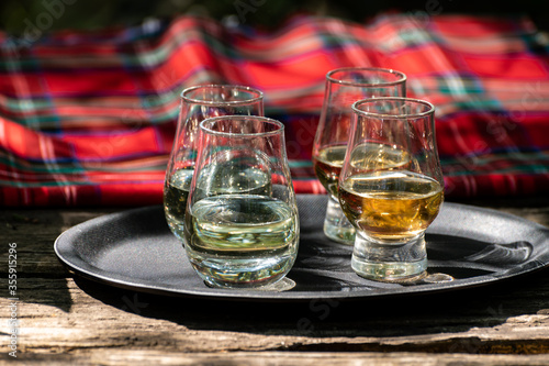 Tasting of different Scotch whiskies on outdoor terrace  dram of whiskey and red tartan