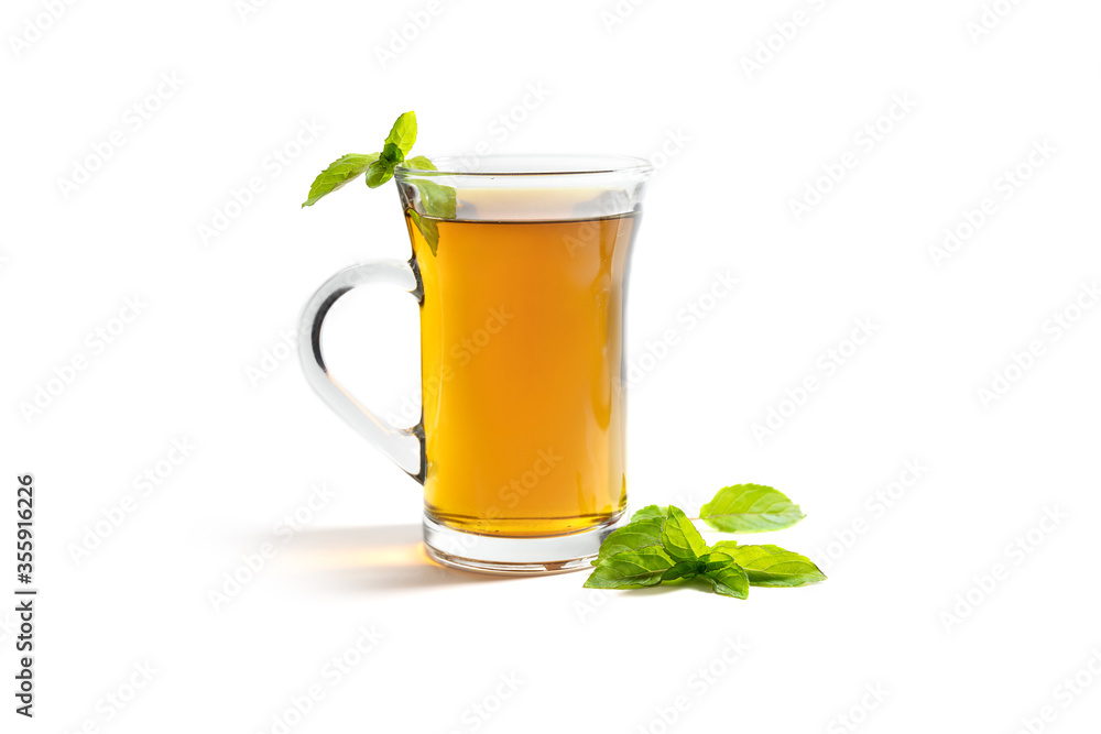herbal tea in a glass mug and a fresh peppermint leaves, healthy drink hot or cold isolated on a white background herbal tea in a glass mug and a fresh peppermint leaves, healthy drink hot or cold isolated on a white background