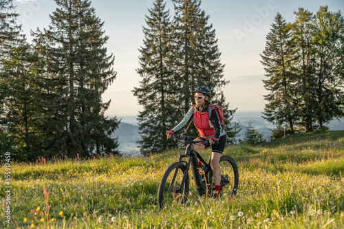 pretty senior woman riding her electric mountain bike on the mountains above Oberstaufen, Allgau Alps, Bavaria Germany 