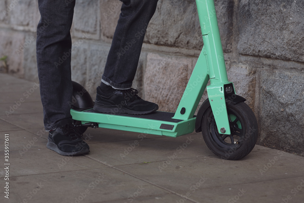 Obraz premium Legs of a man in stylish outfit stand on electric scooter on the street. Electric urban transportation concept image