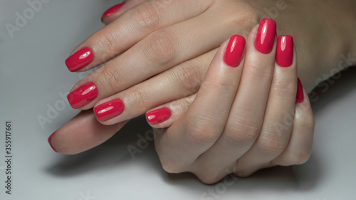 Close up view of female hands with red manicure. Classic red manicure, concept of beauty salon, nails polish.