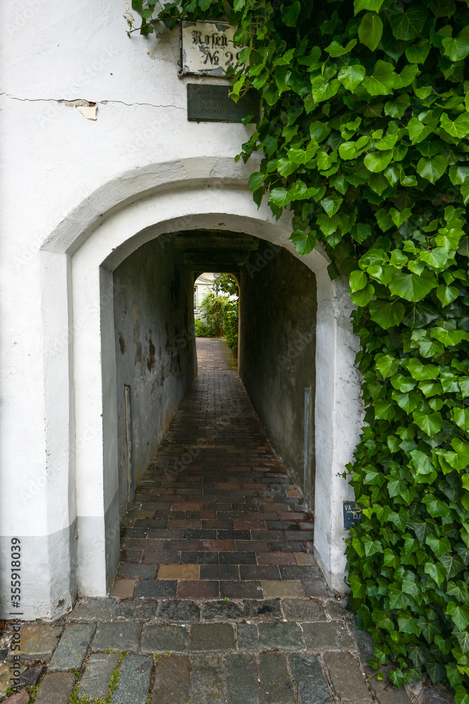 Fototapeta premium Narrow entrance tunnel to a small residential alley, typical tourist destination in the medieval old town of Luebeck, Germany