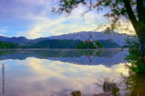 Beautiful morning at Lake Bled and Julian Alps in the background. The lake island and charming little church are famous tourist attraction in Slovenia. Miniature tilt shift lens effect