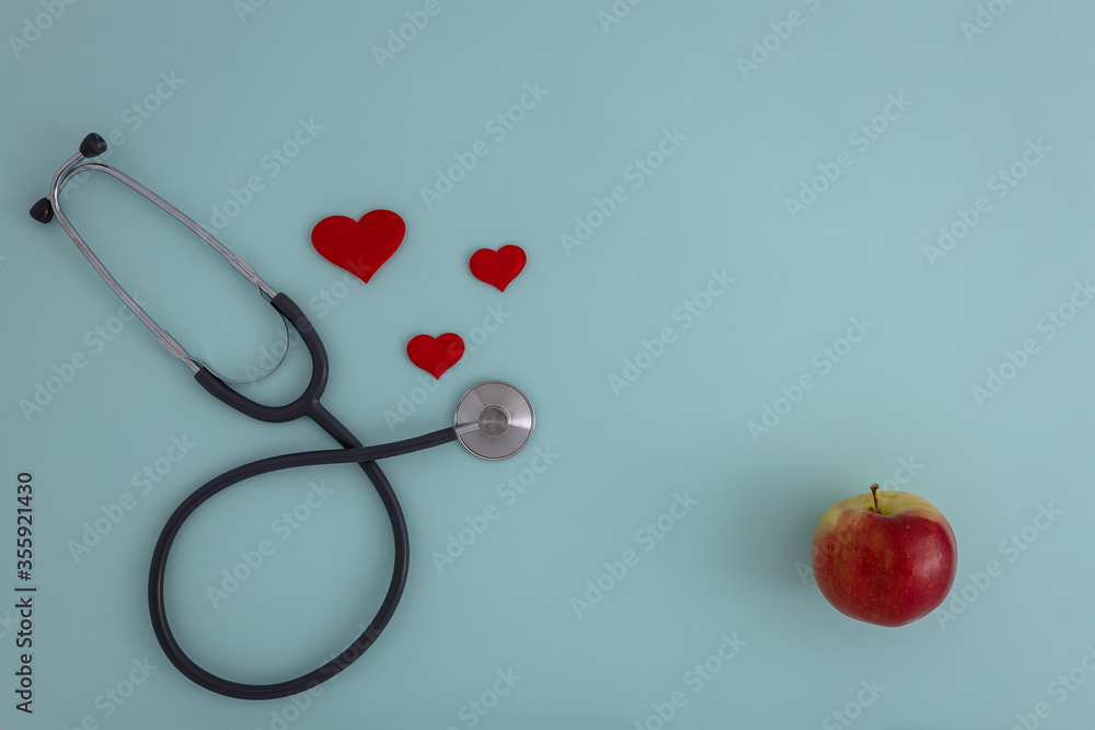 Red heart with stethoscope and Apple on a blue background Red heart with stethoscope and Apple on a blue background